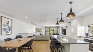 Una cocina moderna con una isla central, taburetes negros y lámparas colgantes.