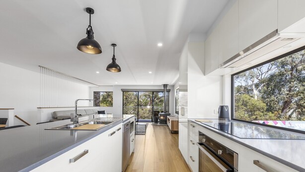 Una cocina moderna con una isla central, electrodomésticos de acero inoxidable y un amplio ventanal con vistas al exterior.