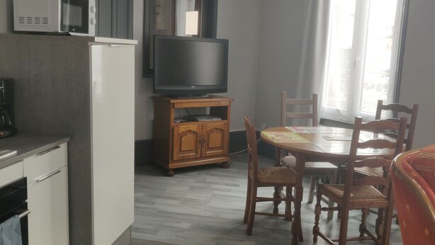 A compact living space with a kitchenette, a dining area, and a television.