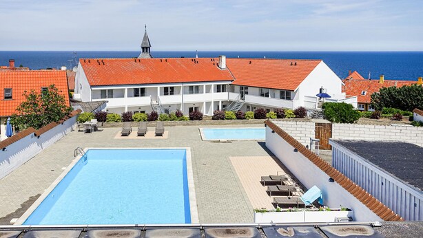 Een hotel met een zwembad, terras en uitzicht op zee.