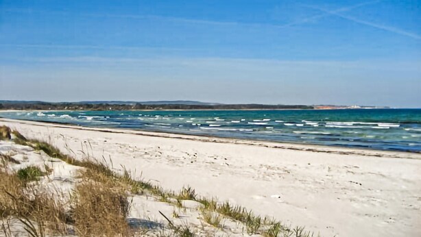 Een strand met wit zand en golven.