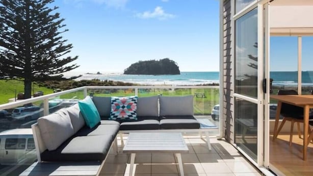 Un balcon avec un canapé, une petite table et une vue sur l’océan.