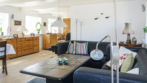 Uma sala de estar moderna com um sofá, mesa de centro e cozinha ao fundo.
