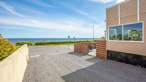 Un edificio moderno con vista al mar, un camino de grava y una valla de madera.