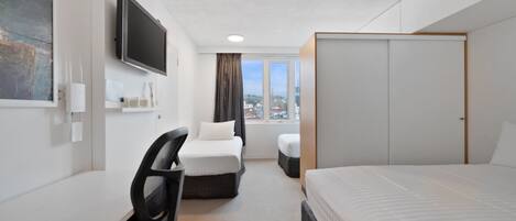 Habitación de hotel con cama, escritorio, silla, televisor y armario.