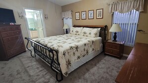 A bedroom with a bed, dresser, nightstand, and a window with curtains. - Private Pool Home Near the Parks (Davenport)