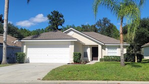 A single-story house with a garage, a front lawn, and a palm tree. - Private Pool Home Near the Parks (Davenport)