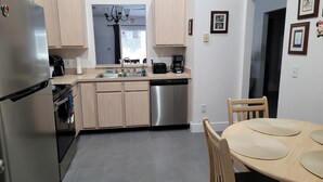 A modern kitchen with stainless steel appliances, wooden cabinets, and a dining area with a round table and chairs. - Private Pool Home Near the Parks (Davenport)