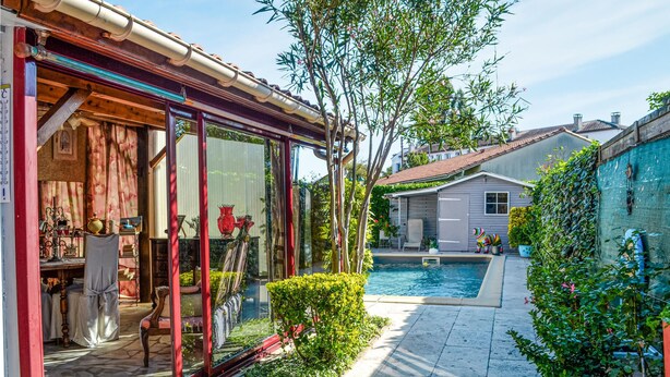 A private pool area with a glass enclosure, a small garden, and a building with a tiled roof. - Stunning home in Bergerac (Bergerac)