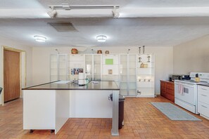 A modern kitchen with a central island, white cabinetry, and a microwave.