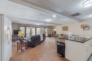 A spacious living area with a sofa, a television, and a dining table.