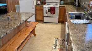 Una cocina con armarios de madera, un refrigerador blanco, un microondas, una estufa y un lavaplatos.