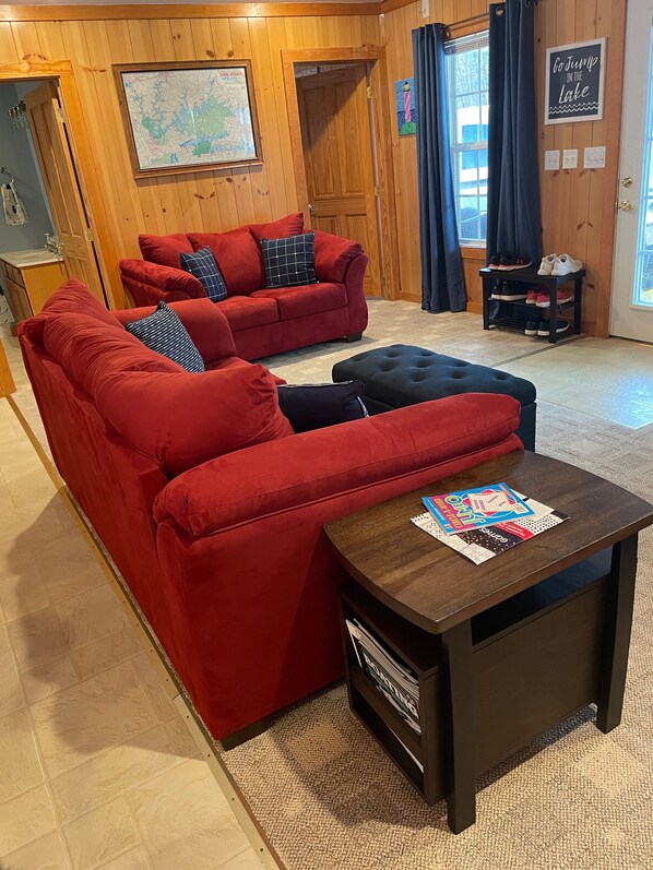 Una sala de estar acogedora con sofás rojos, una mesa de centro de madera oscura y un mapa en la pared.