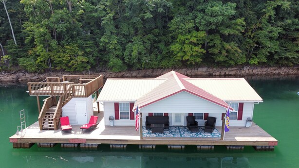 Una casa flotante con terraza, mobiliario exterior y una bandera.