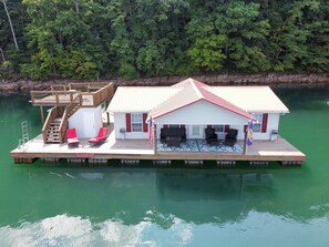 Una casa flotante con terraza, mobiliario exterior y una bandera.