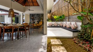 A modern interior with a dining area, a seating bench, and a bamboo wall. - Villa Waha (Canggu)
