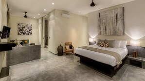A modern bedroom with a large bed, a wooden chair, a desk, and a painting on the wall. - Villa Waha (Canggu)