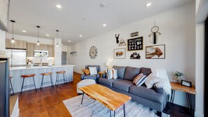 A modern kitchen with a central island, bar stools, and pendant lighting. - Welcome to Mountain Dreams + River Streams! (Silverthorne)