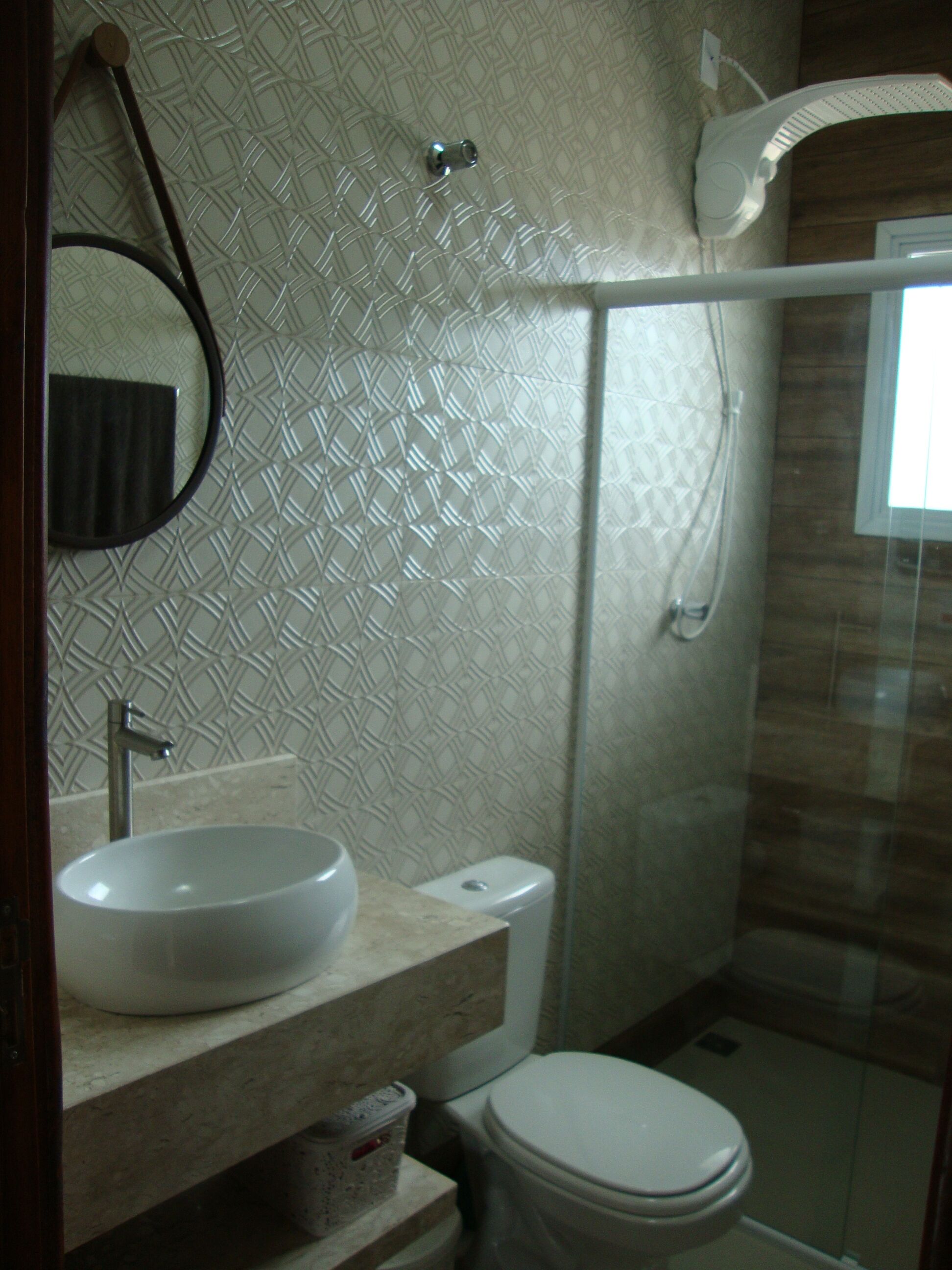 A bathroom with a round sink, a toilet, and a shower area.