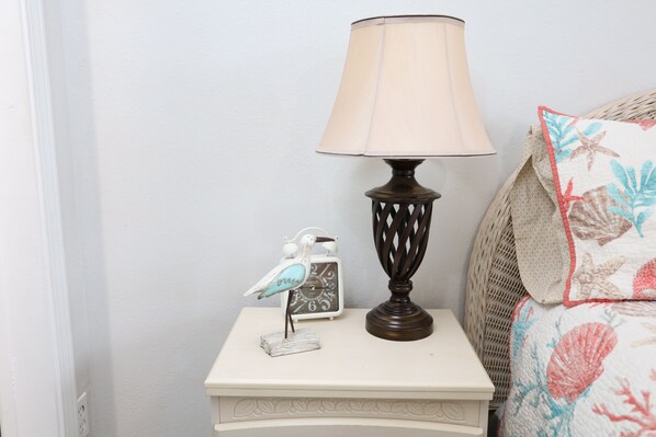 A bedside table with a lamp, a decorative bird figurine, and a clock.