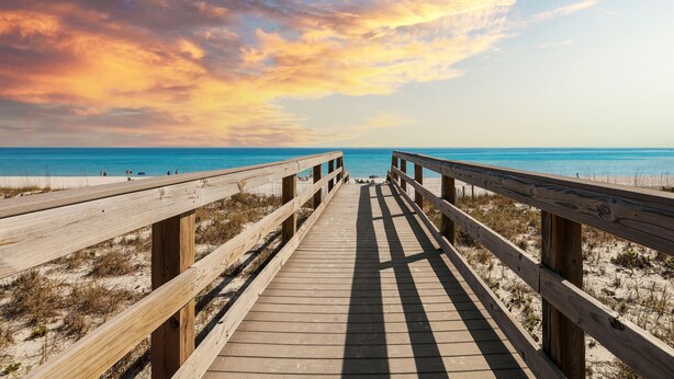 A wooden boardwalk leading to a beach with clear skies and a sunset. - Emerald Shores: Steps from the Gulf, Navarre Beach (Navarre)