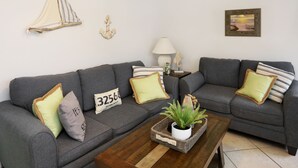 A living room with two grey sofas, a wooden coffee table with a plant, and decorative pillows. - Emerald Shores: Steps from the Gulf, Navarre Beach (Navarre)