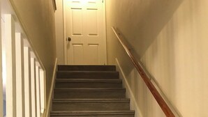 A staircase with wooden steps and white railings leading to a door. - Emerald Shores: Steps from the Gulf, Navarre Beach (Navarre)