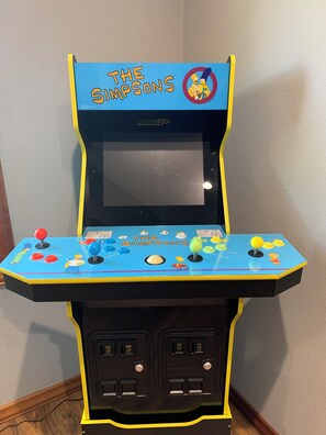 A The Simpsons arcade game machine with a blue and yellow color scheme, featuring characters and game controls.