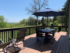 A deck with a table and chairs, an umbrella, and a view of the landscape.