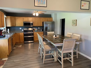 A modern kitchen with wooden cabinets, stainless steel appliances, and a dining area with a wooden table and chairs.