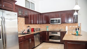 Una cocina con armarios de madera oscura, electrodomésticos de acero inoxidable y salpicadero de azulejos.
