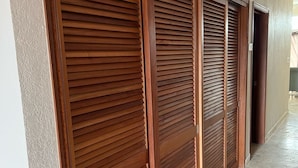 Un pasillo con puertas correderas de madera, suelo de baldosas y una pared lisa.