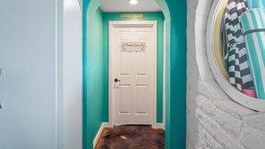A hallway with a teal wall, a white door, and a sign that reads "A Mermaid's Crossing." - The Mermaid Studio (New Port Richey)