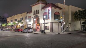 A building with a large arched entrance, a sign that reads "Theater," and a street with parked cars. - The Mermaid Studio (New Port Richey)