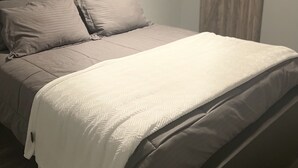 Un dormitorio con cama, cabecera y ventana con cortinas.