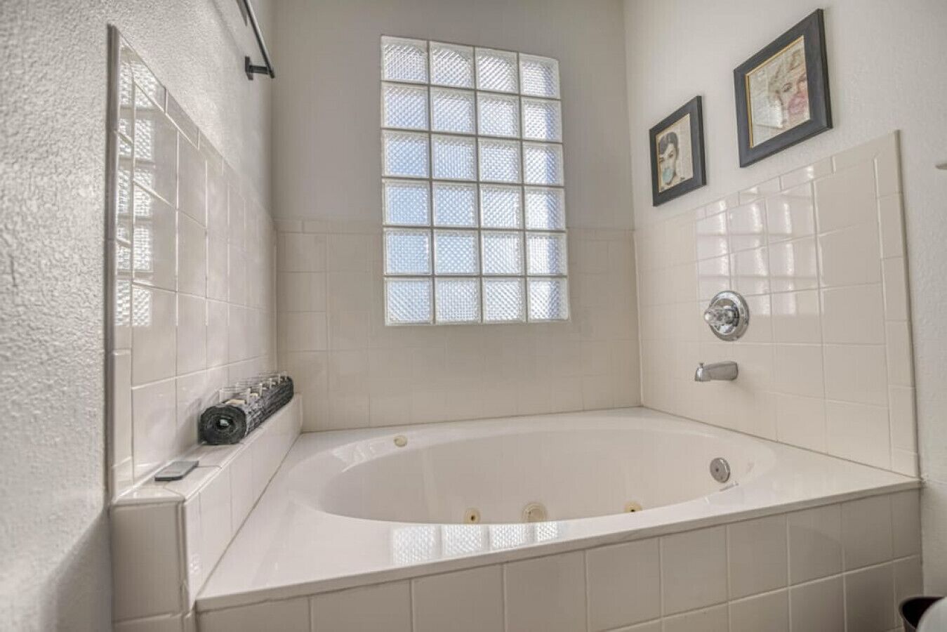 Ein Badezimmer mit einer großzügigen Badewanne, einem Fenster mit Gittermuster und einer Duschkabine.