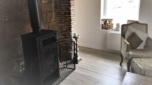 A rustic room with a brick fireplace, a wooden chair, and a window with a view.