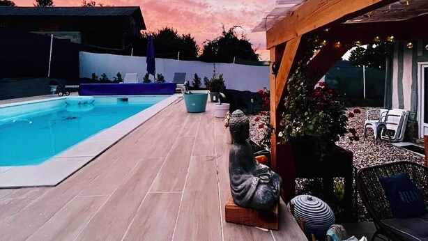 A backyard with a swimming pool, a wooden pergola, and outdoor seating.