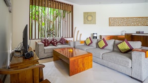 A modern living room with a grey sofa, wooden coffee table, and a television on a wooden stand.