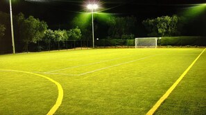 A well-lit sports field with a goalpost, surrounded by trees and a fence. - "melograno" Holiday Home With Swimming Pool and Private Beach (Mattinata)