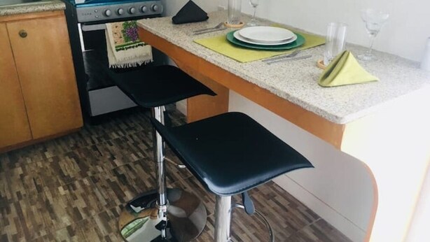 A kitchen with a stove, sink, and bar stools. - Room-bahamas Petapat Suite (Nassau)