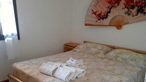 A bed with a wooden frame, a pull-out drawer, and a folded towel on the bed. - Spectacular Sea View Sardinia! 300m From The Sea! (Quartu Sant'Elena)