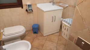 A small bathroom with a toilet, sink, and a blue trash bin. - Spectacular Sea View Sardinia! 300m From The Sea! (Quartu Sant'Elena)