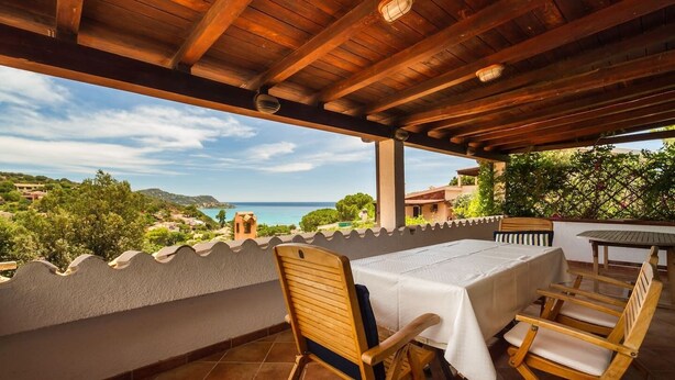 A covered outdoor dining area with a table and chairs, overlooking a scenic landscape with a view of the sea and hills. - Spectacular Sea View Sardinia! 300m From The Sea! (Quartu Sant'Elena)
