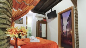 A hotel room with a bed, a mirror, a vase with flowers, and a door with a scenic view. - Trastevere, Pretty,central,economic (Rome)