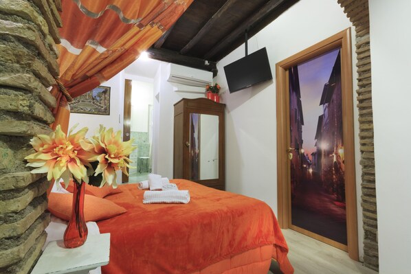 A hotel room with a bed, a mirror, a vase with flowers, and a door with a scenic view.