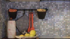 A kitchen with a tiled backsplash, a hanging rack with kitchen towels, a basket of fruit, and a wooden cutting board. - Trastevere, Pretty,central,economic (Rome)