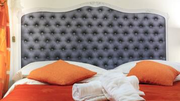 A bed with a tufted headboard, two orange pillows, and a red bedspread.