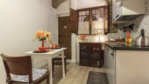 A compact kitchen with wooden cabinets, a dining table with chairs, and a small island with a kettle. - Trastevere, Pretty,central,economic (Rome)