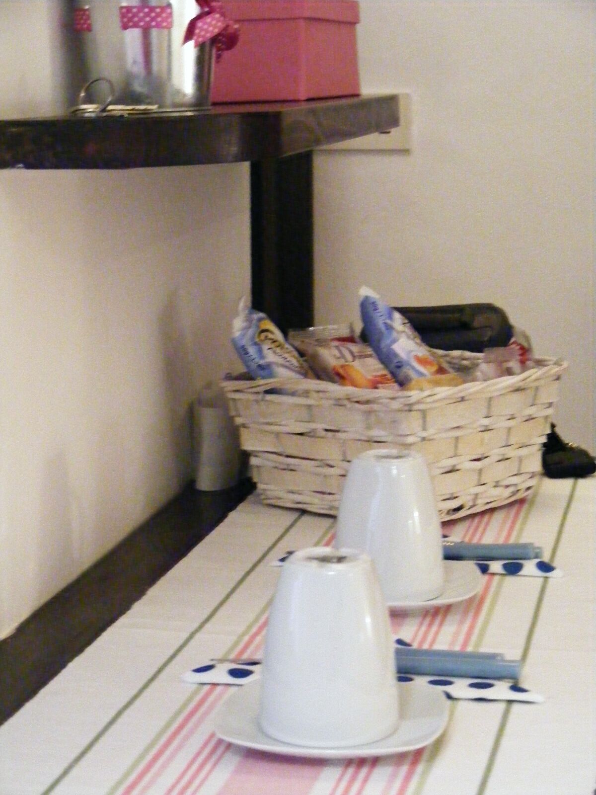 A table with plates, cups, and a basket of snacks.